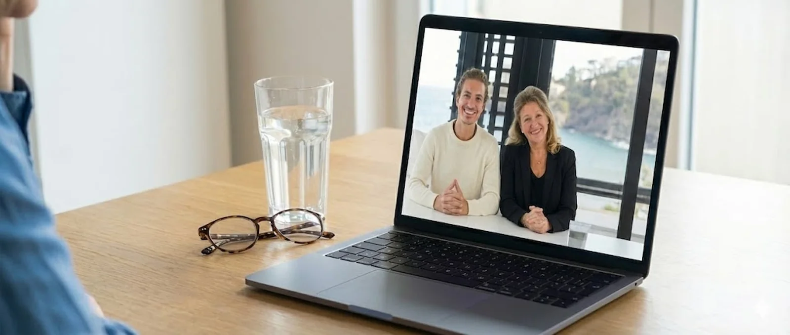 Persönliches Coaching im Videocall: zwei Trainer auf einem Laptopbildschirm, davor Brille und Wasserglas